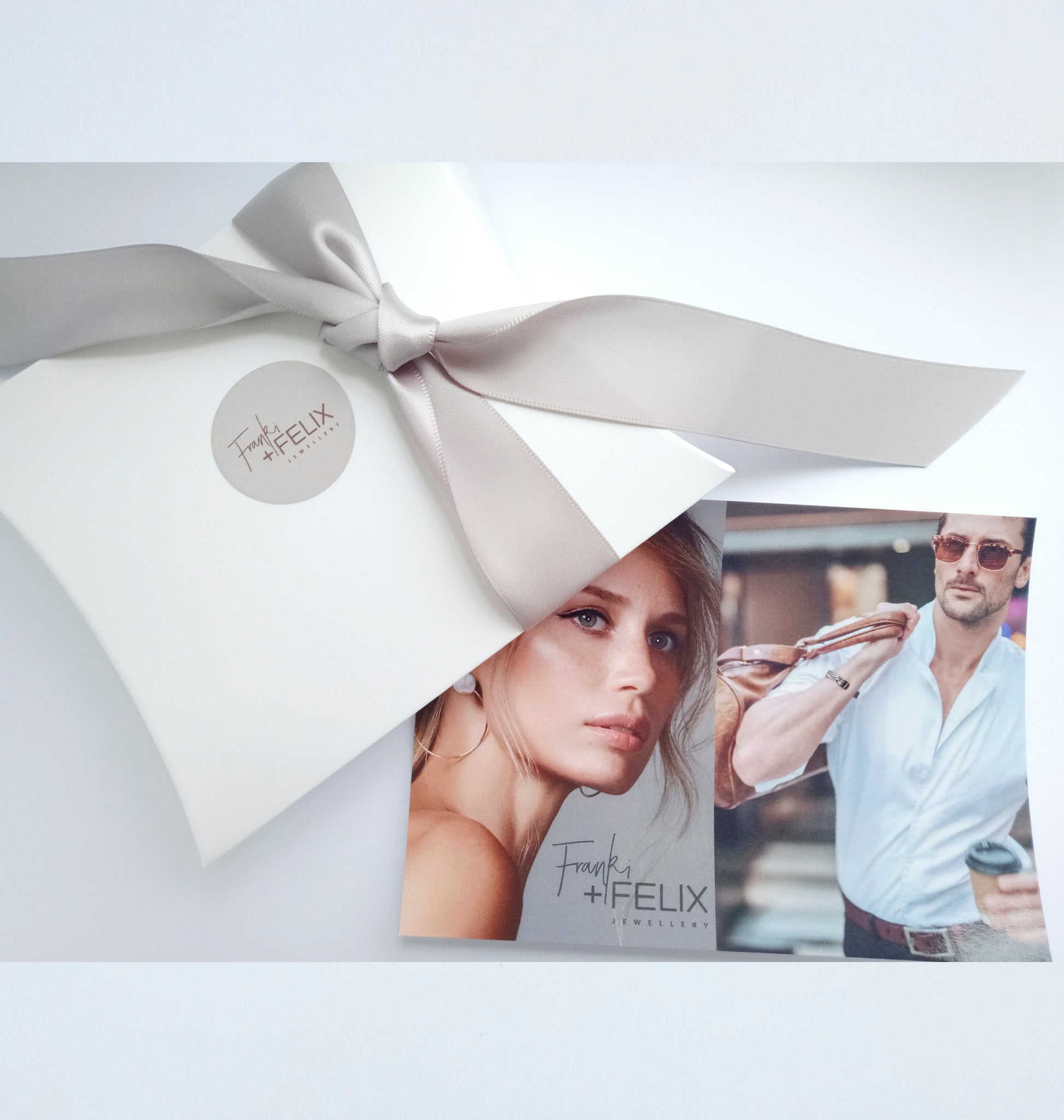 white pillow gift box with grey logo on front grey ribbon glossy postcard franki and felix jewellery